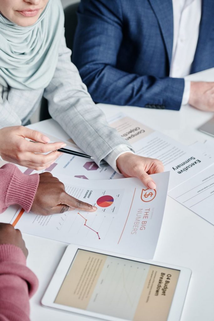 hands of persons holding paper printouts on a table