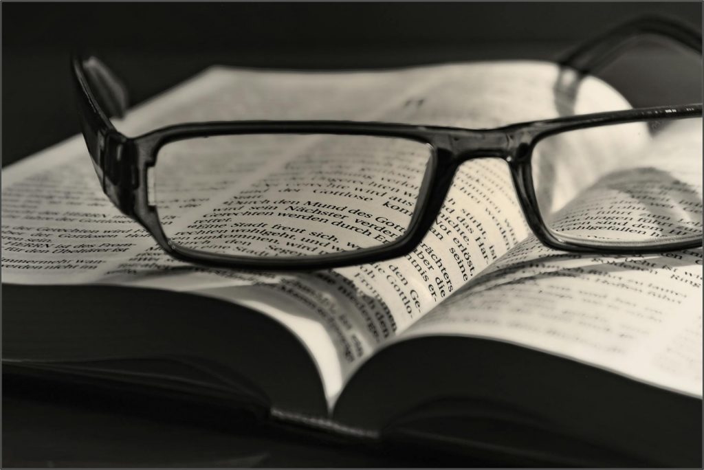 black eyeglasses placed on white book
