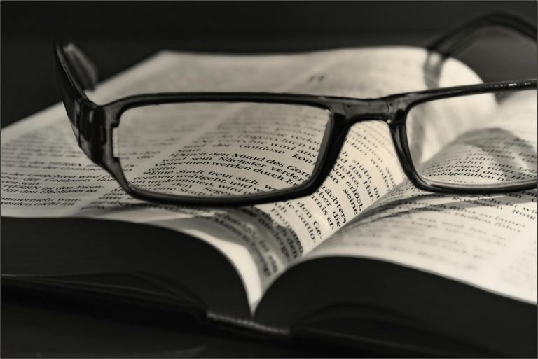 black eyeglasses placed on white book