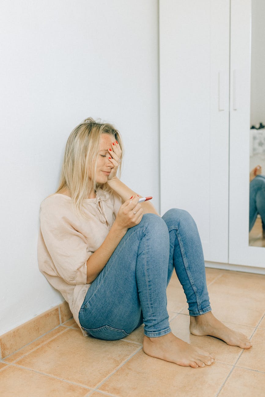 a woman looking hopeless while holding a pregnancy test