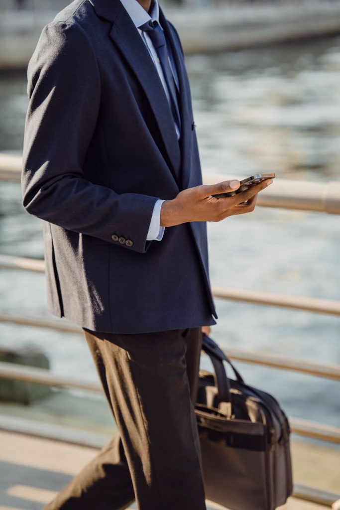 man walking and holding a bag and a phone