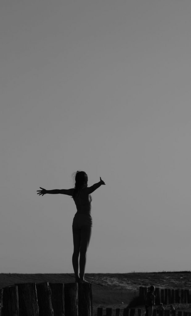 grayscale photo of woman standing on log