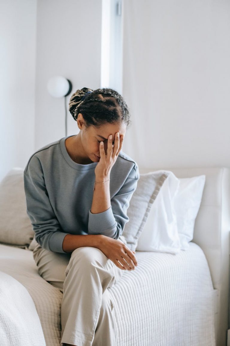 anxious black woman covering face with hand on bed