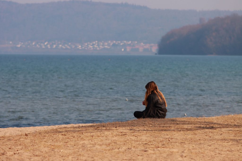 a woman sitting on the beach sand