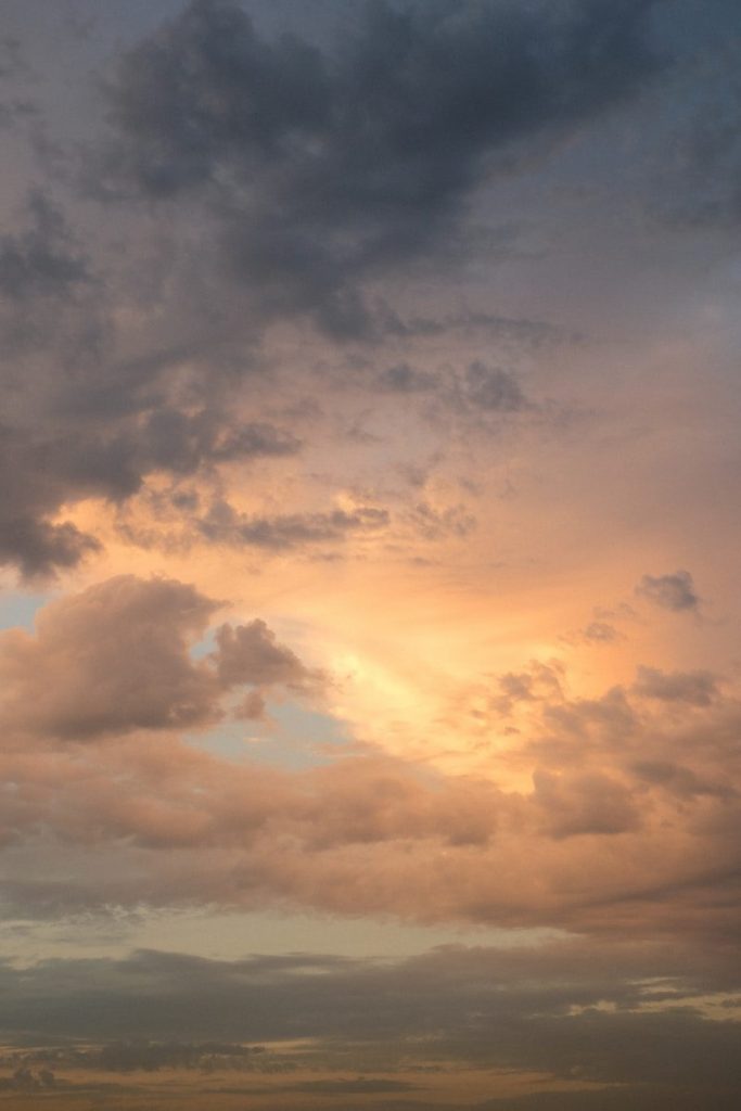 Clouds illuminated by warm golden light against a soft blue sky.